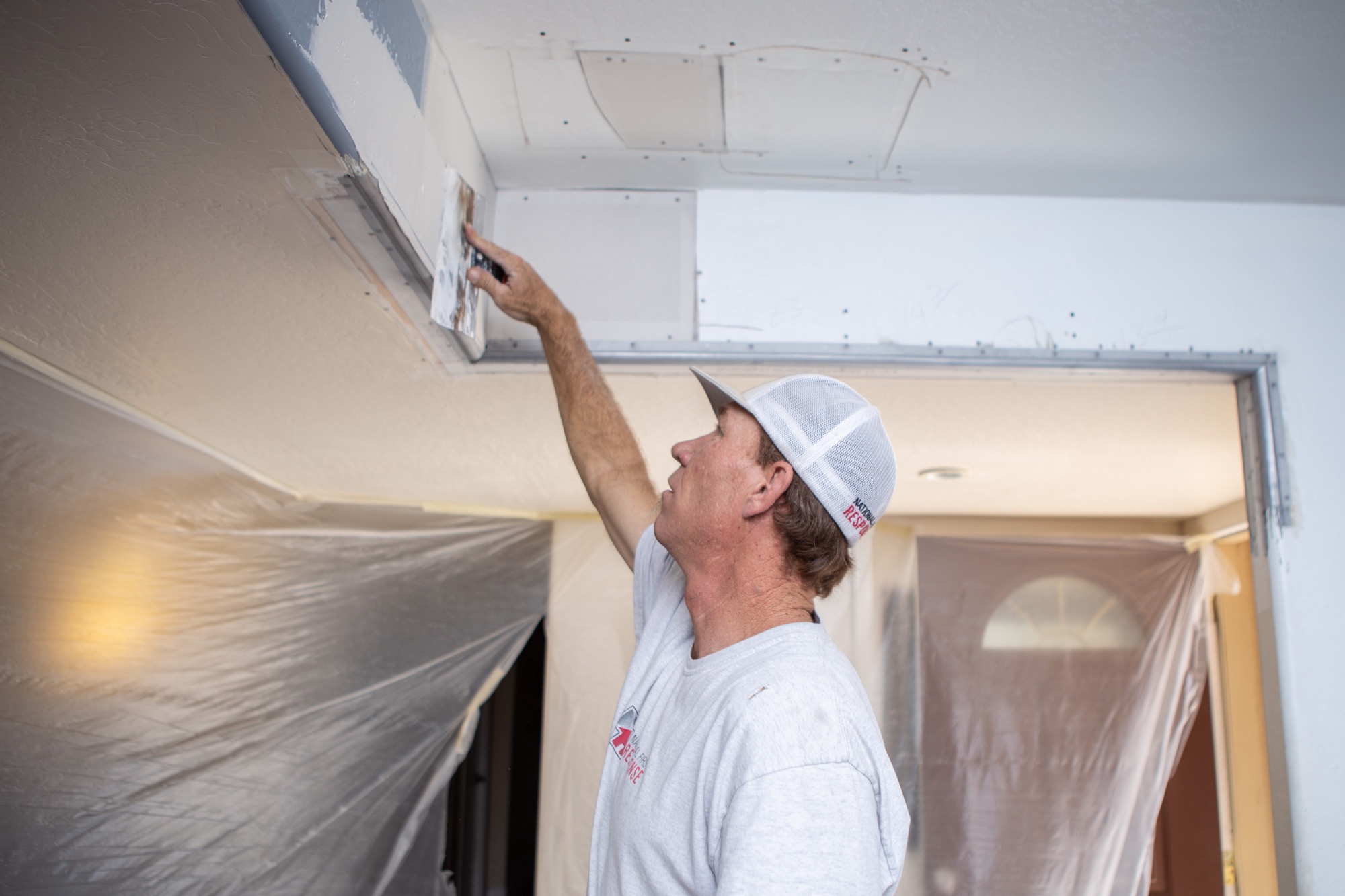 Technician completing drywall repairs after property damage