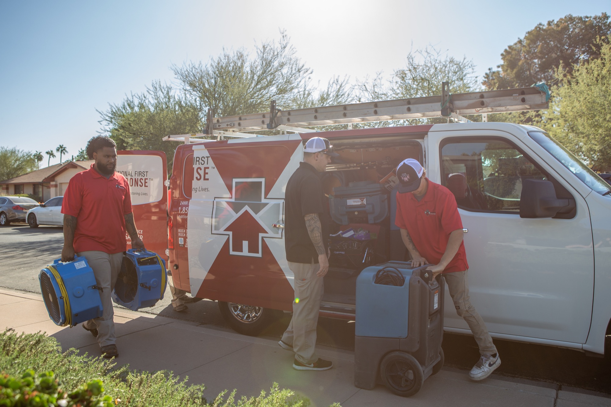 National First Response technicians carrying drying equipment from a service van