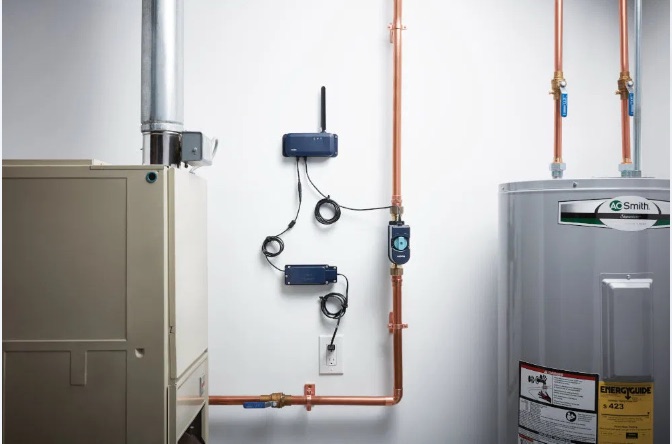 Moen Flo smart water shutoff installed on copper plumbing beside a water heater